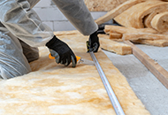Worker cutting insulation for the attic