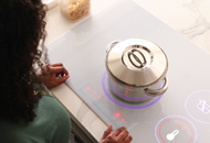 overhead picture of woman standing next to an induction stovetop.