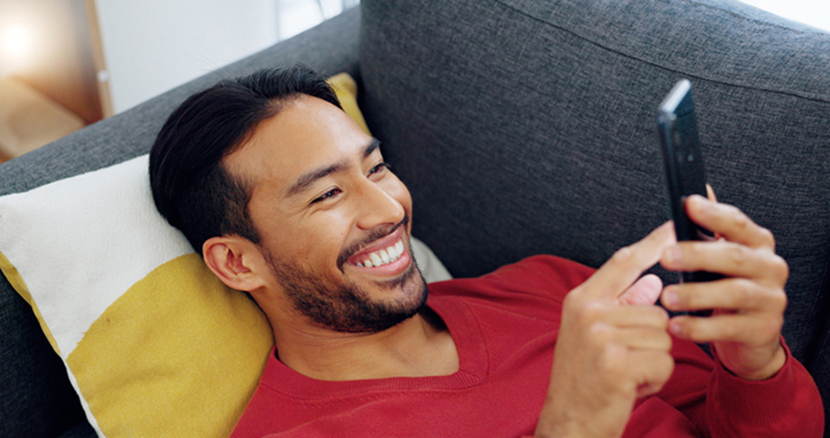 Man on couch smiling at his cellphone