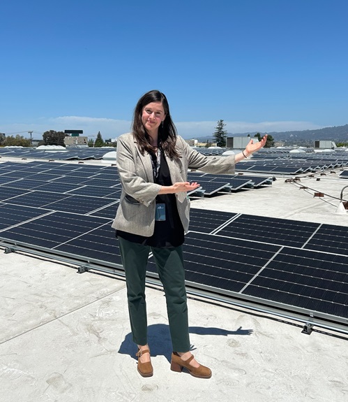 Director Fleisher poses in front of a rooftop solar array.