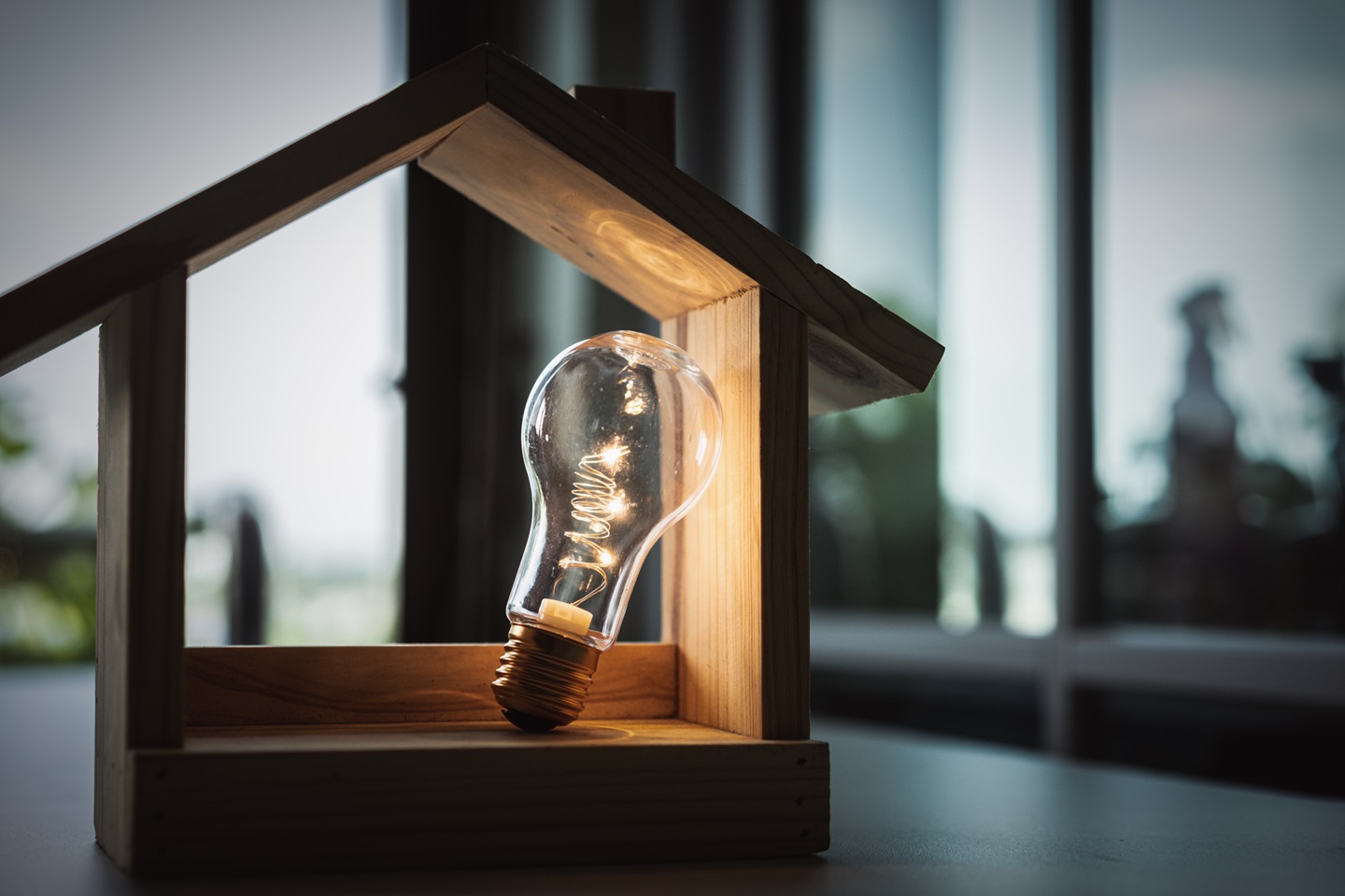 Lit up lightbulb inside a model of a house