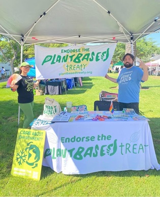 CPUC employee stands under a tent promoting the Plant Based treaty organization. 