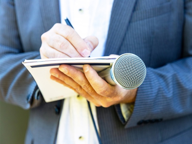male reporter taking notes and holding a microphone