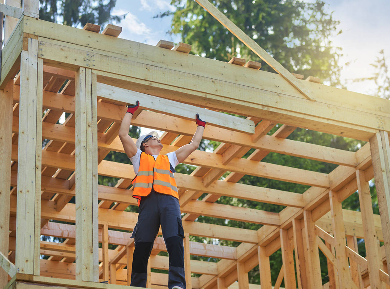 A construction worker wears safety gear while framing a house.